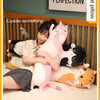 A person is cuddling several plush cat pillows, including pink, black, and orange cats, on a bed.