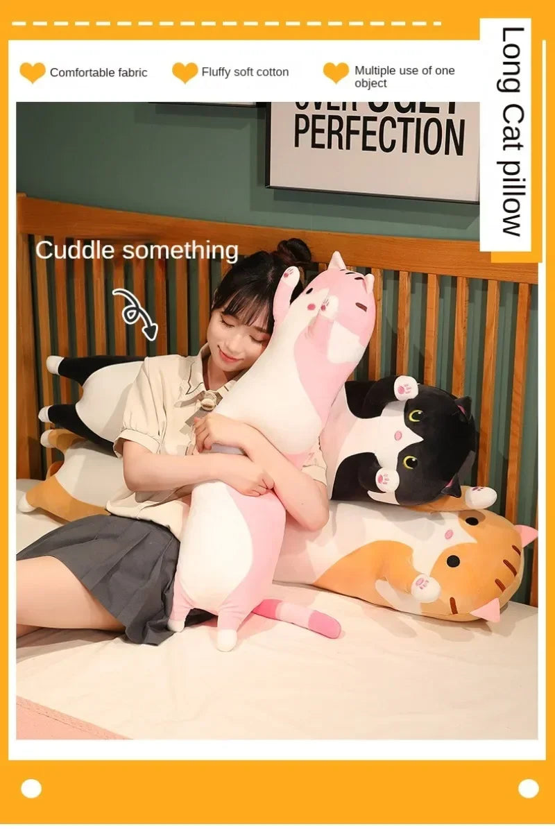 A person is cuddling several plush cat pillows, including pink, black, and orange cats, on a bed.