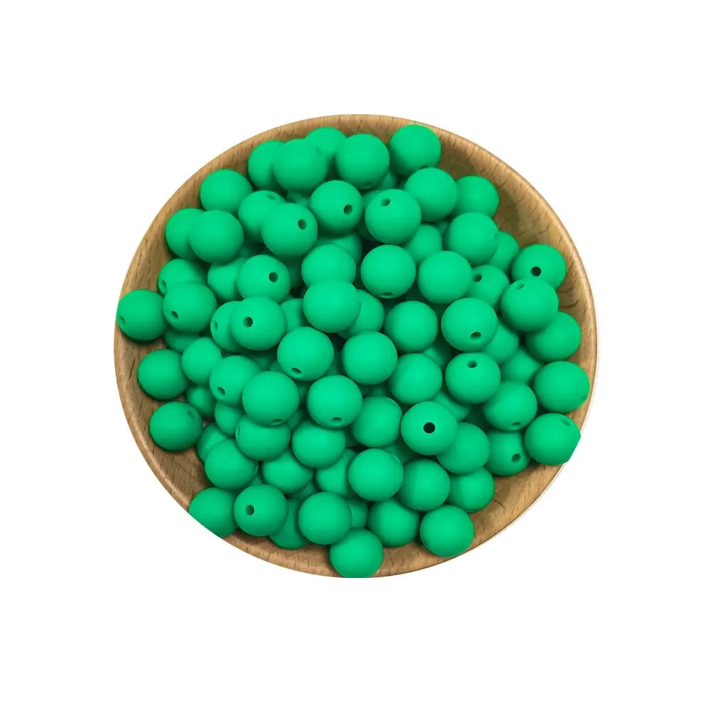 A wooden bowl filled with numerous bright green silicone round beads for jewelry making and DIY crafts