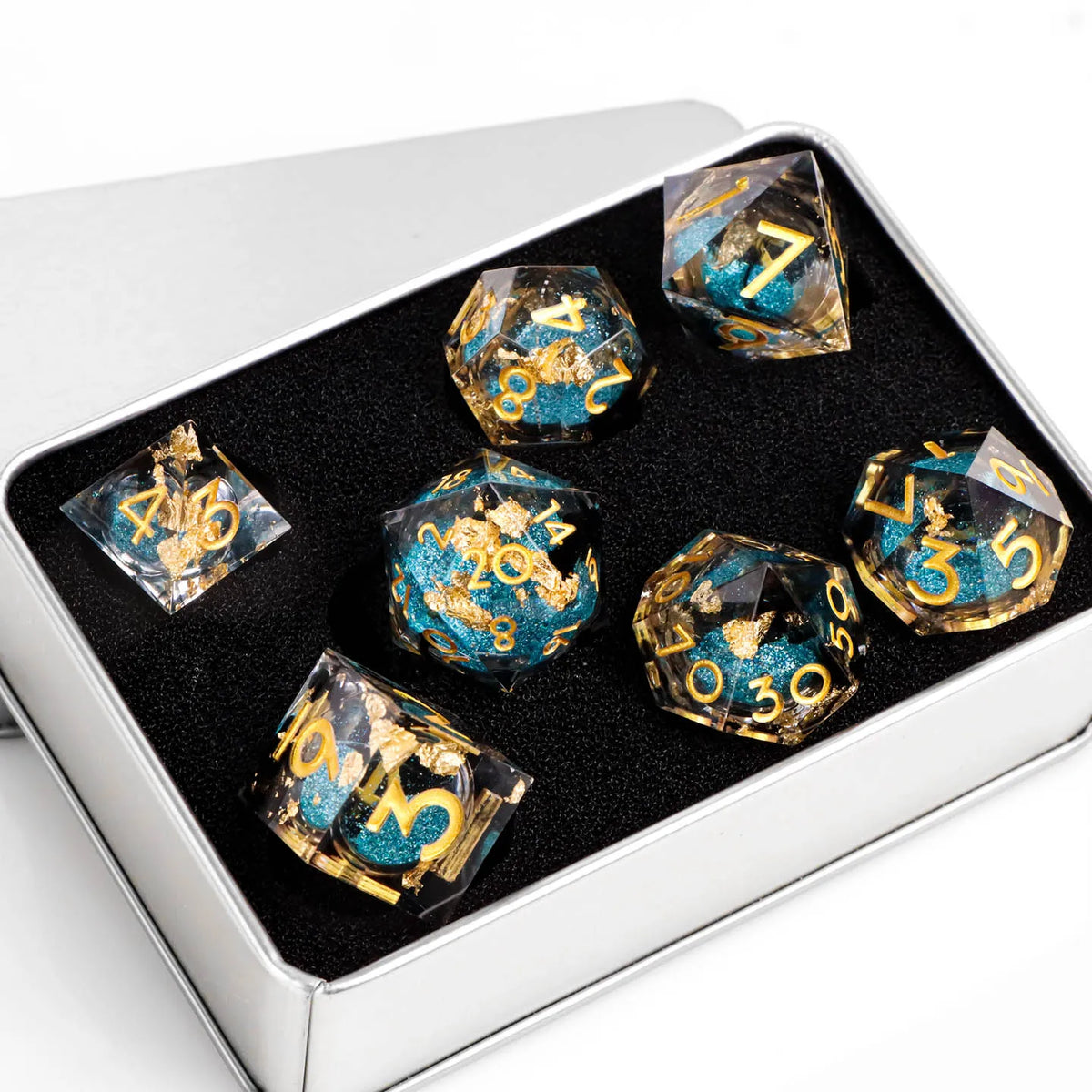 A set of ten translucent resin dice with gold accents displayed in a silver box.