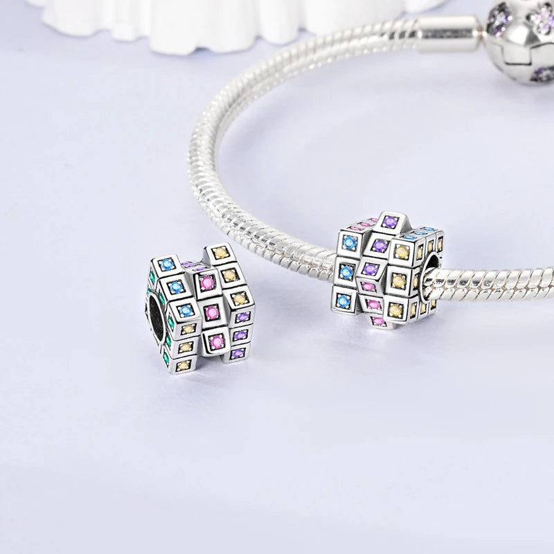 A silver rotatable Rubik's cube charm attached to a bracelet chain.