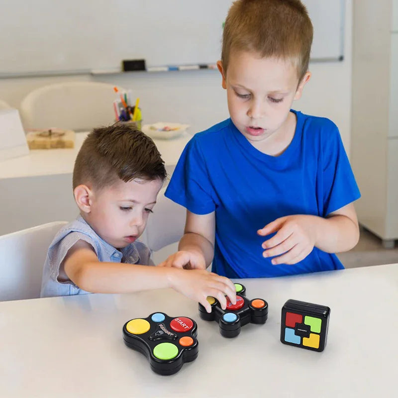 A young boy is playing a light-up memory game with sounds on a white table.