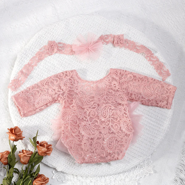 A pink lace bodysuit with puff sleeves is displayed on a white textured cloth.