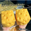 Two yellow cheese squishy fidget toys are held in hands against a blurred background.