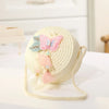 A light cream handwoven straw crossbody bag featuring a pink lace bow and sheer fabric accents.
