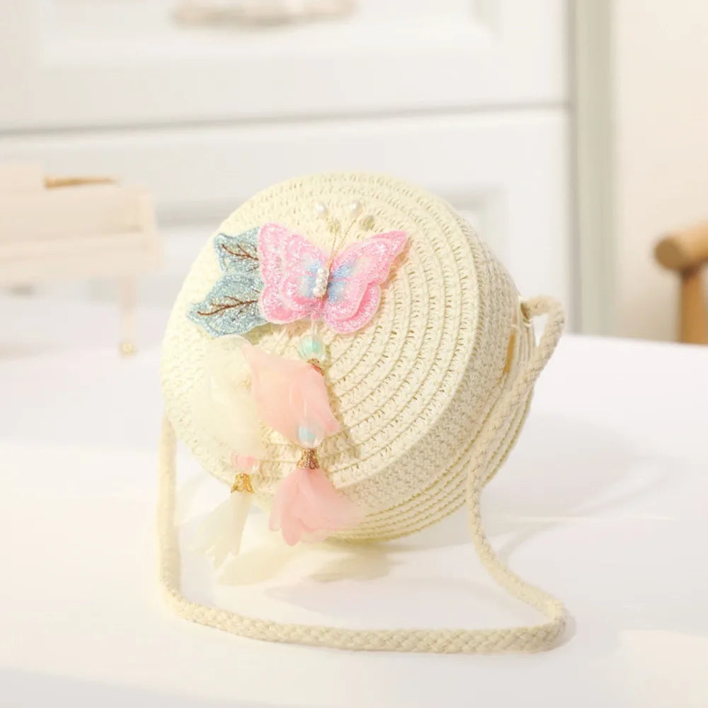 A light cream handwoven straw crossbody bag featuring a pink lace bow and sheer fabric accents.