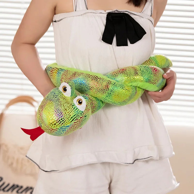 A person is holding a bright green cartoon snake plush toy with large eyes and textured skin.