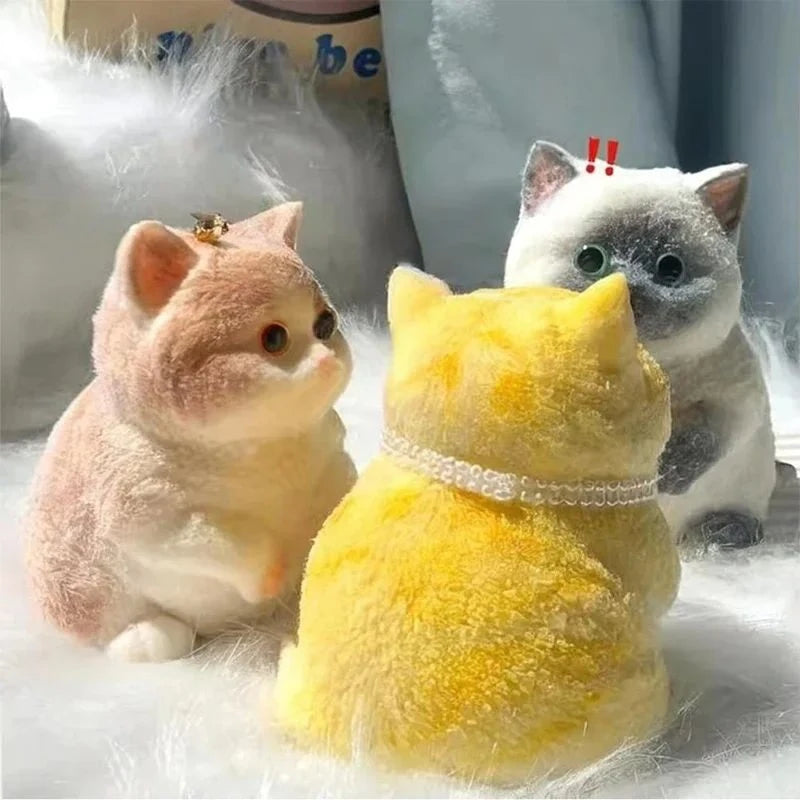 A fluffy yellow cat shaped squishy stress relief toy sitting next to a gray and white cat toy.