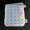 A clear plastic storage container holds 30 round bottles of various colored liquid or solid materials.