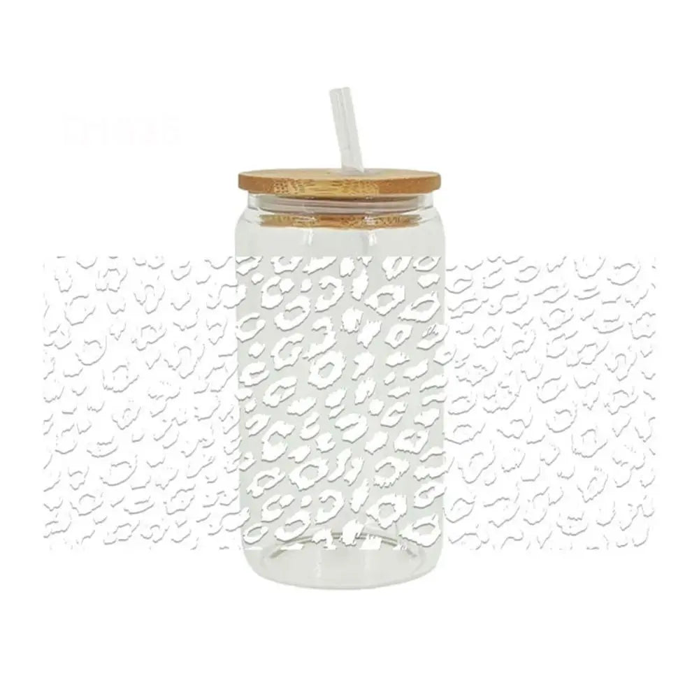 A clear glass jar with a lid and a straw, filled with leopard print UV DTF cup wraps.