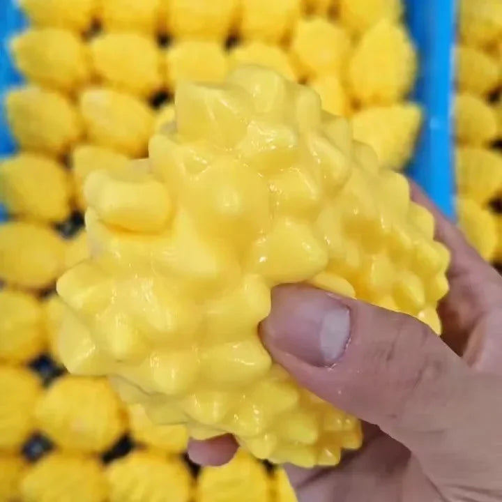 A hand is squeezing a bright yellow, squishy toy shaped like a dog noodle.