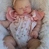 A newborn baby doll with hand-painted skin is lying in a fluffy white fur setting.