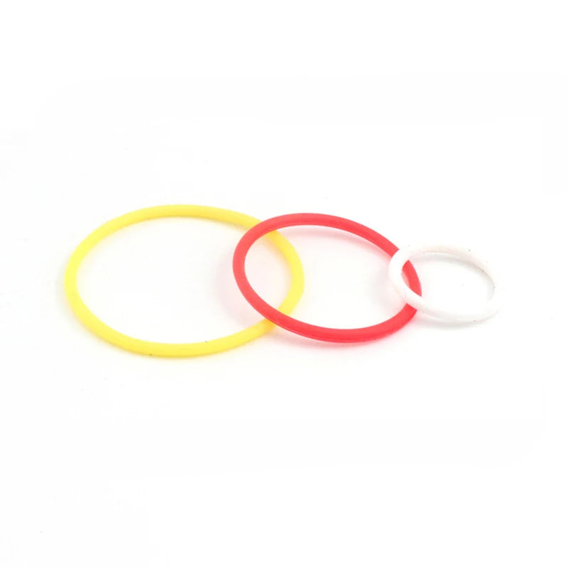 Three colored rubber bands, yellow, red, and white, laid out on a white background.
