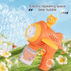 An orange bear-shaped automatic bubble gun is shown spraying bubbles in a grassy outdoor setting.
