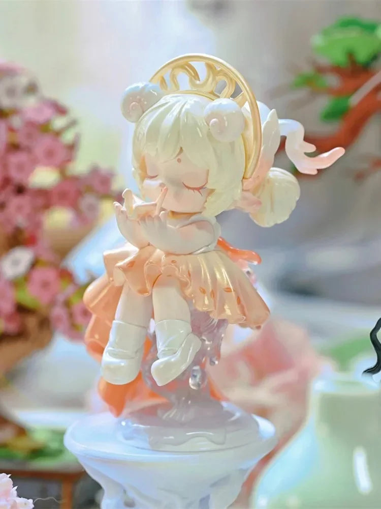 A white and peach collectible figurine of a girl with blonde hair and a golden halo.