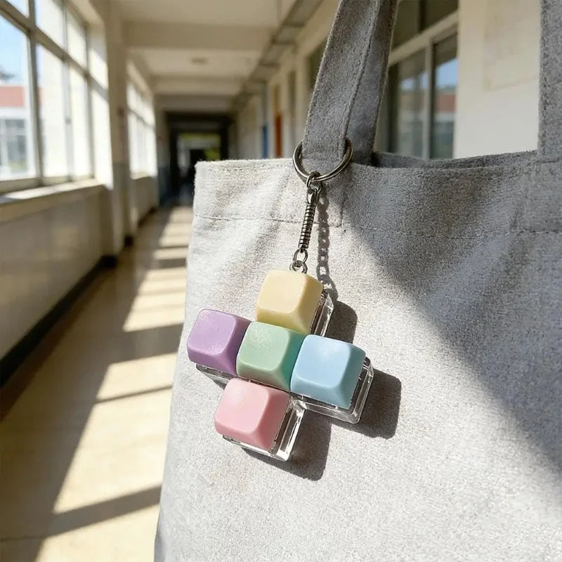 A keychain featuring five colorful, translucent silicone fidget cubes attached to a gray fabric bag.