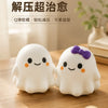 Two white squishy ghost stress balls with purple bows resting on a wooden surface.