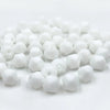 A pile of small, white faceted bicone crystal glass beads for jewelry making.