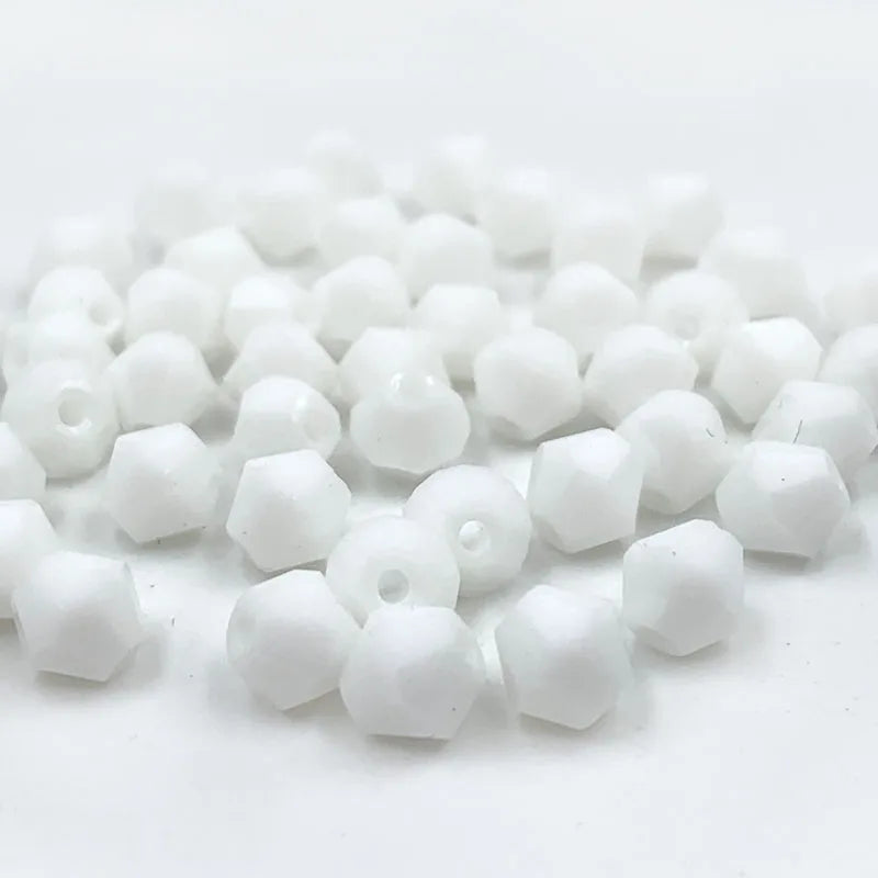 A pile of small, white faceted bicone crystal glass beads for jewelry making.