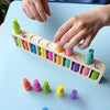 Hands are placing colored wooden puzzle pieces into a wooden board for a matching game set.