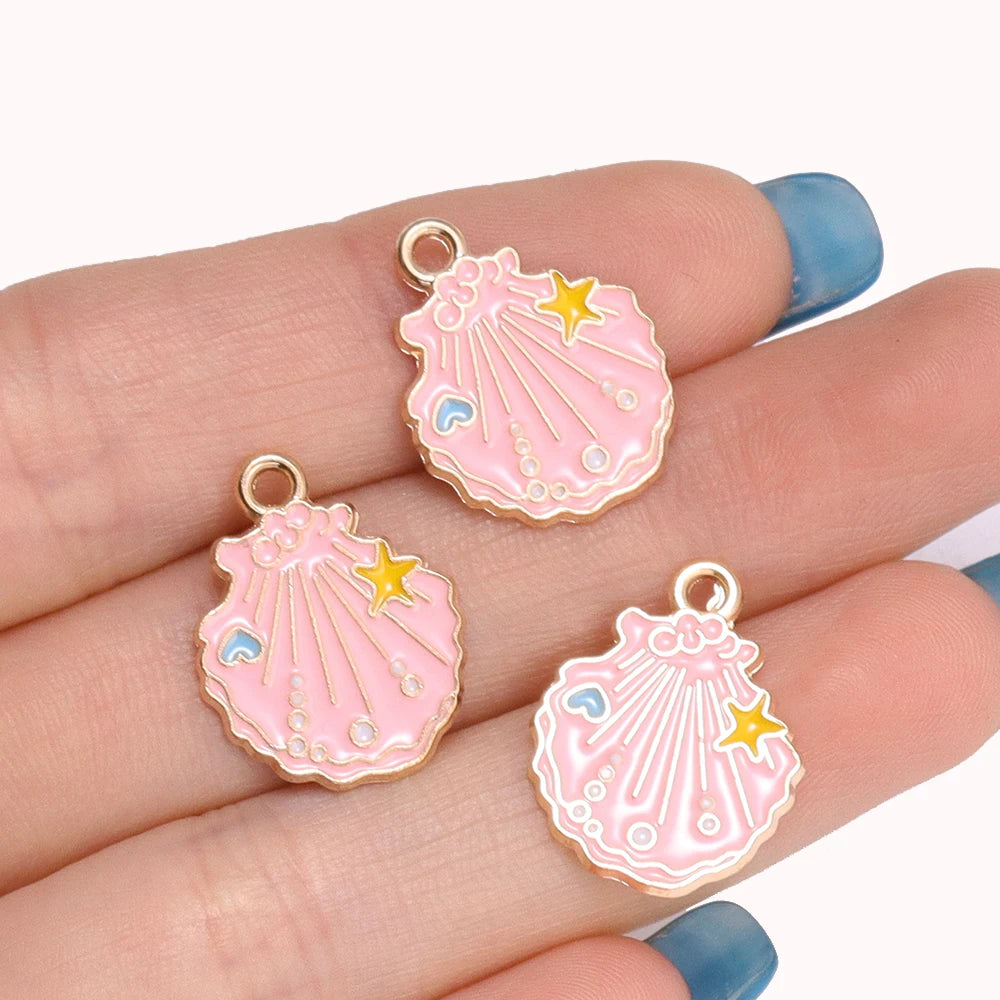 Pink enamel starfish charms with gold-colored findings displayed on a hand.