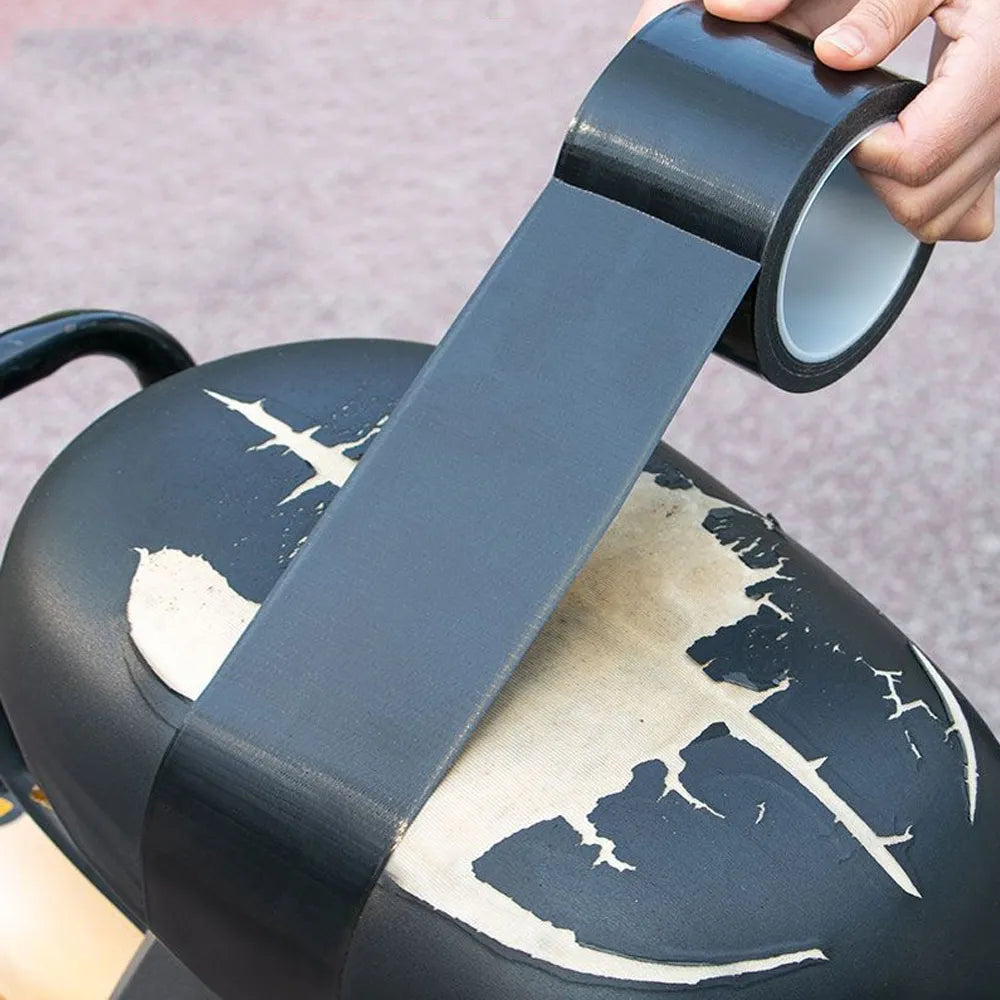 A hand is applying a strip of dark gray self-adhesive leather repair tape to the lid of a black pot.
