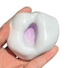 A hand holds a white, squishy sand stress ball with a purple interior for sensory fidgeting.