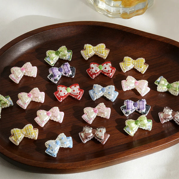 A collection of colorful acrylic jewelry findings beads shaped like bows arranged on a dark wooden platter.