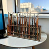 A wooden organizer holding numerous art brushes and pencils arranged in slots on a white table.