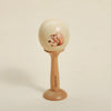 A wooden bear musical instrument set featuring a carved bear on a smooth, light-colored ball mounted on a wooden stand.