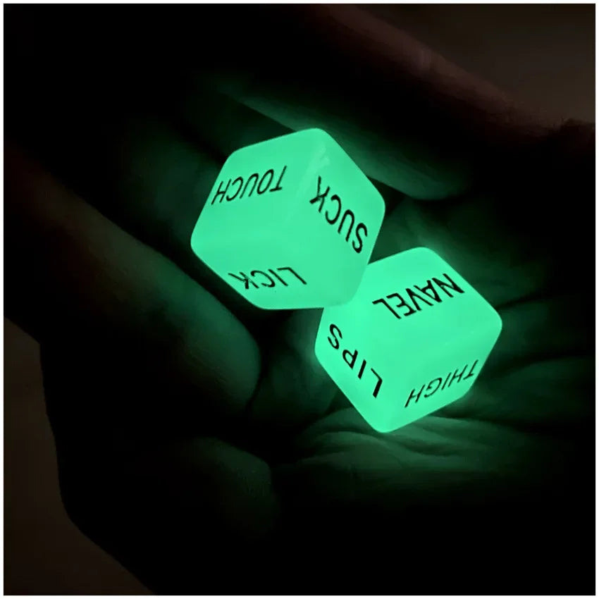 Three glowing green dice labeled with body parts are held in a hand against a dark background.