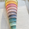 A vertical stack of pastel colored wooden blocks, ranging from yellow to teal.