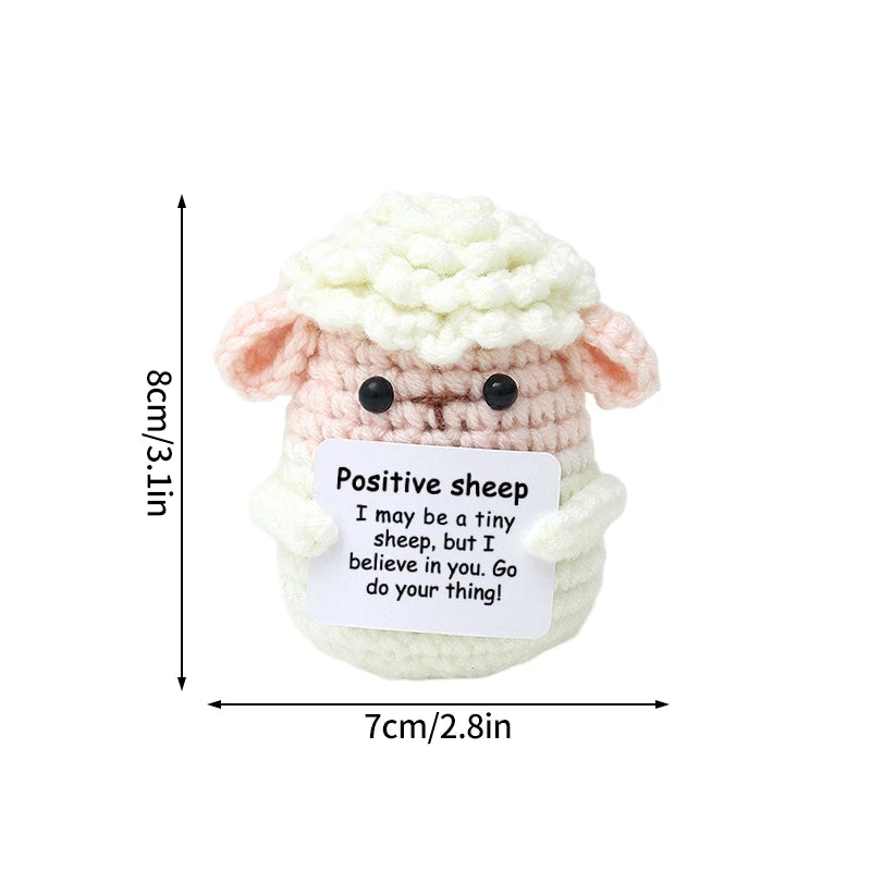 A handmade crochet sheep doll with a fluffy white wool texture and an inspirational message tag.