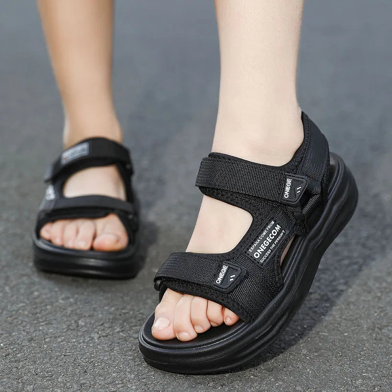 A pair of black boys' non-slip summer sport sandals worn on a person's foot.