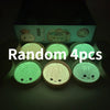 Four glowing green squishy dumpling toys are displayed in a box.