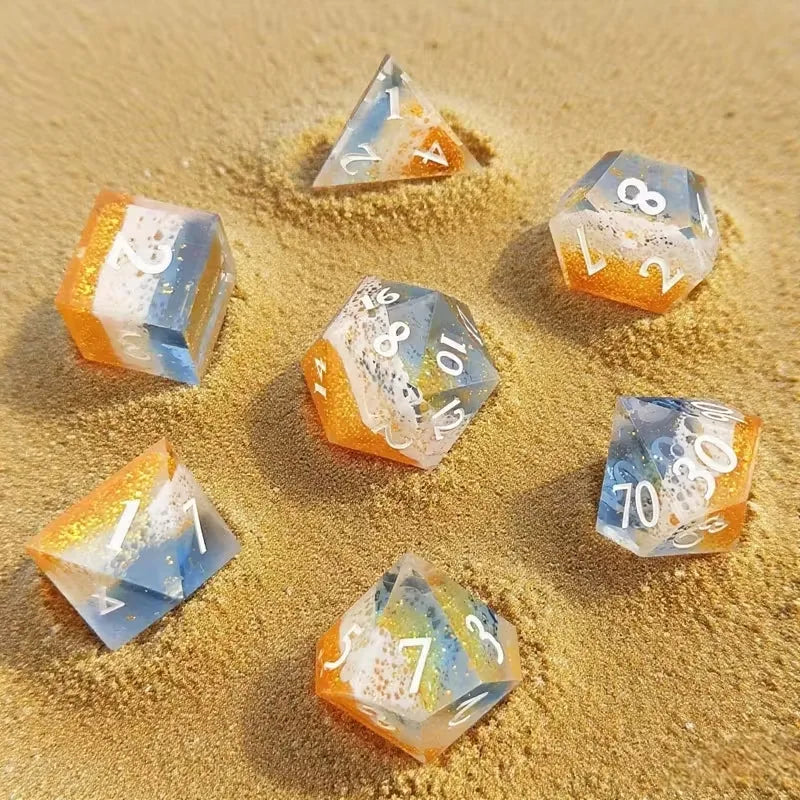 A collection of translucent resin dice in various colors and designs scattered on sand.