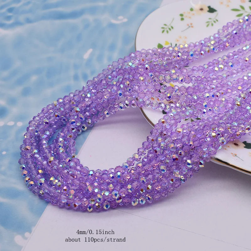 Purple faceted crystal rondelle beads for jewelry making strung together on a white surface