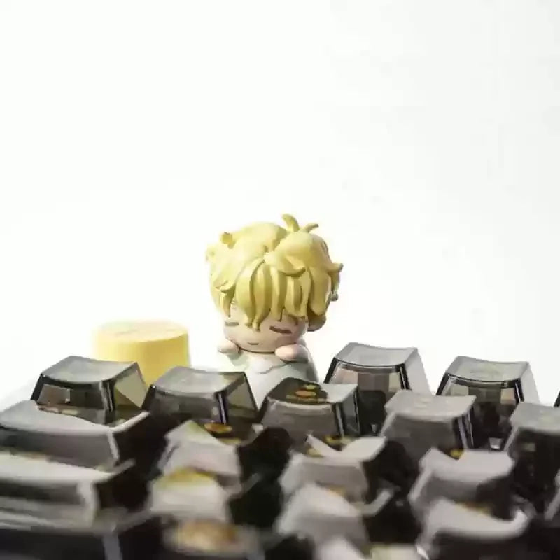 A close-up of a yellow Alien Stage Baby Series collectible keycap blind box with a small figure.