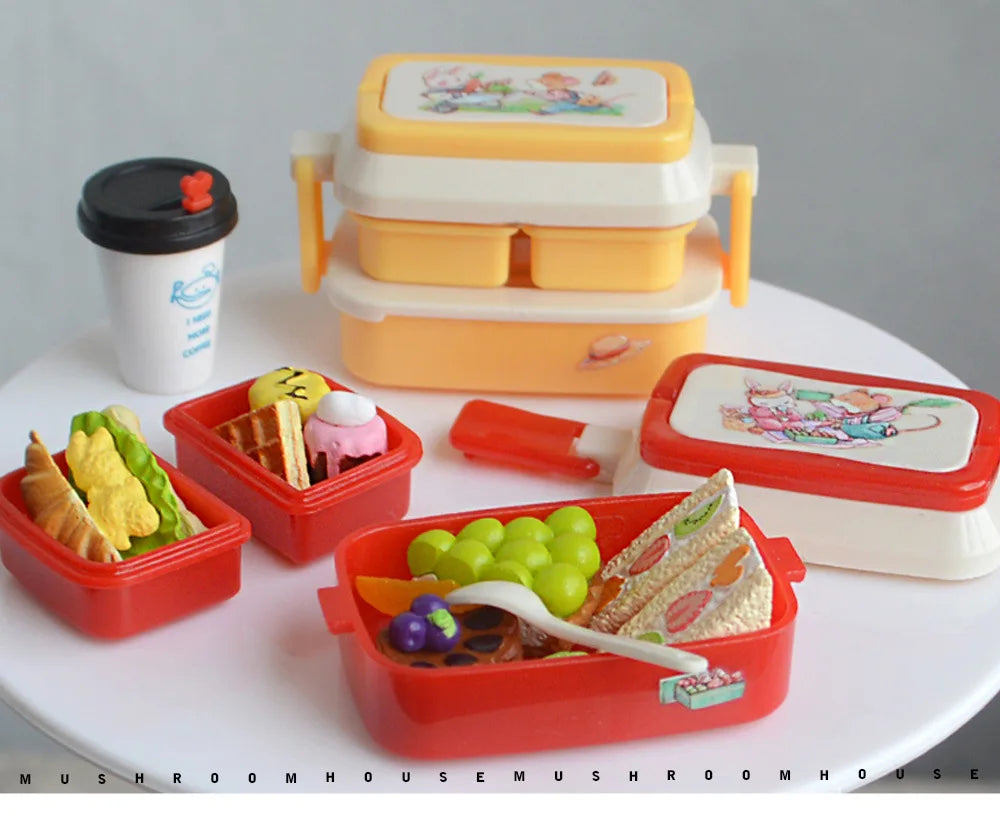 A set of miniature doll picnic lunch boxes in yellow, white, and red colors with handles and food items.