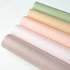 A stack of twenty tissue paper sheets in pastel shades, including pink, peach, and green.