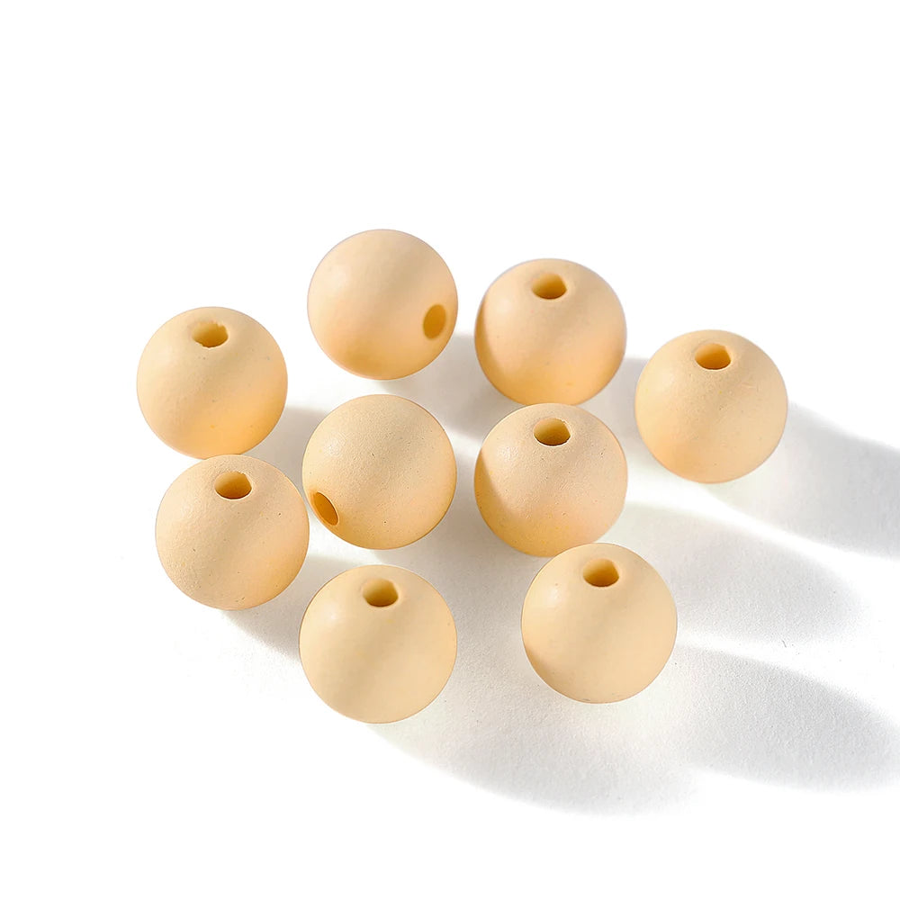 A collection of matte acrylic round beads in a natural beige color scattered on a white background.