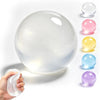 A hand holds a clear silicone squishy stress ball next to a row of colorful, translucent oil bubbles.
