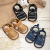 A pair of navy blue soft non-slip baby sandals for first walkers, displayed on a light wooden surface.