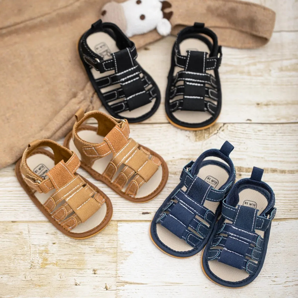 A pair of navy blue soft non-slip baby sandals for first walkers, displayed on a light wooden surface.