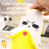 A yellow and white plush toy resembling a face with expressive features is shown against a background of stacked books.