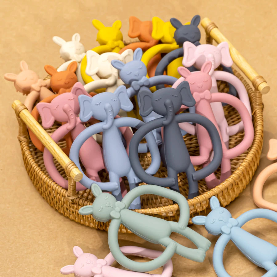 A basket filled with various silicone teething toys for babies and children in pastel colors like pink, yellow, purple, and g
