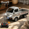 A silver RC truck model is shown on a rug next to its remote control, with a wooden crate in the background.