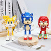 A blue Sonic the Hedgehog building block toy standing on a wooden base next to a yellow fox toy.