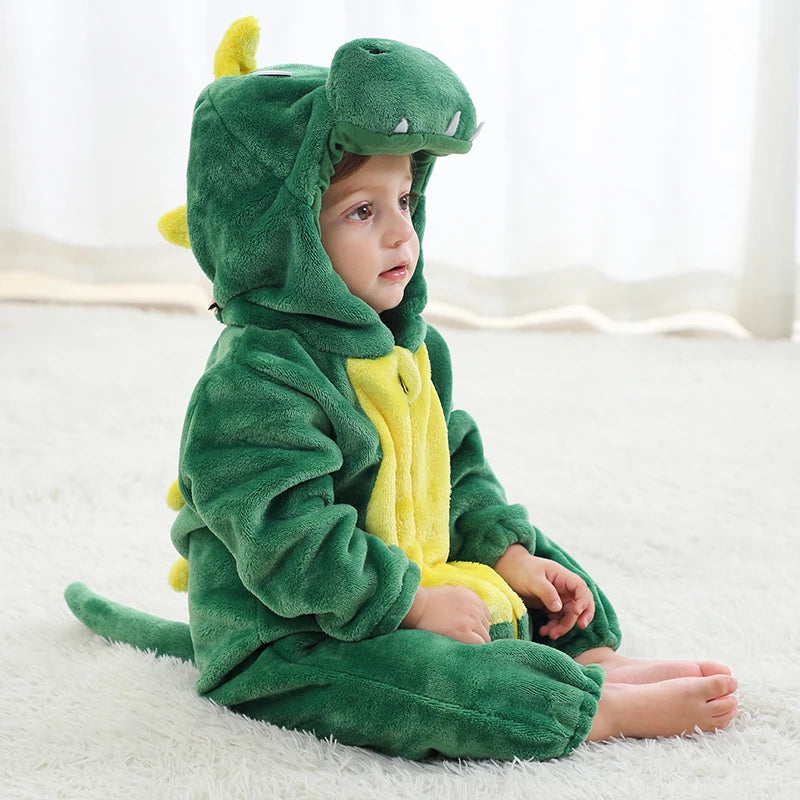 A baby wearing a green hooded romper resembling a dinosaur, sitting on a white rug.