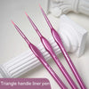 A set of five pink triangle handle liner pens with gold tips resting on a white surface.